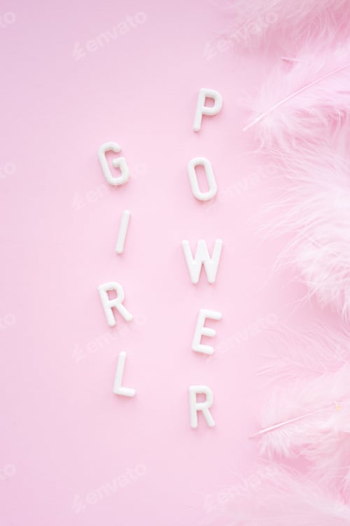 Preview: Vertical Inscription: girl power from white plaster letters on a pink background with feathers.