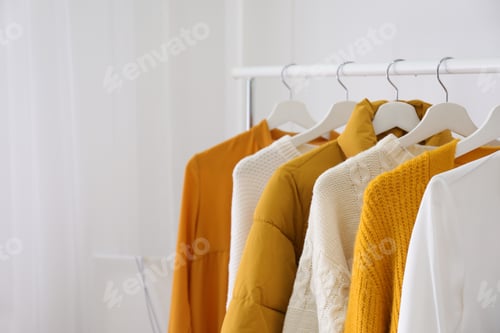 Preview: Rack with stylish warm clothes indoors, closeup. Space for text