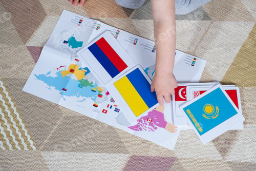 Preview: The hand of a small child lays out the flags of the countries of the world nearby