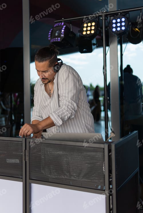 Vista previa: DJ masculino tocando música en un evento. Imagen vertical.