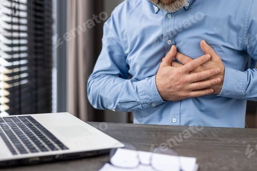 Preview: Man experiencing chest pain while working on a laptop in an office environment