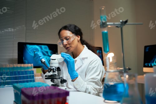 Preview: Female scientist conducting research using microscope in laboratory