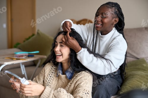 Preview: Two smiling women braiding hair at home