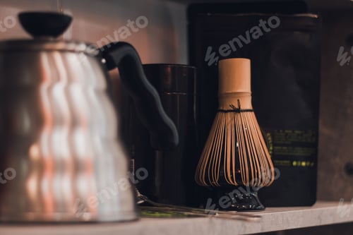 Preview: Shot of a bamboo whisk for matcha tea on a kitchen countertop next to a kettle