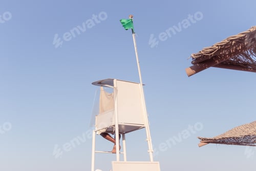 Preview: A green flag flies over the white lifeguard tower in the sky
