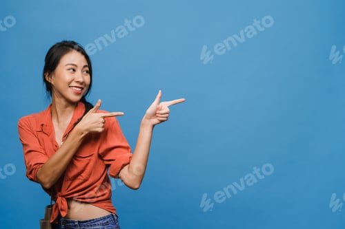 Preview: Asian lady smiling with cheerful expression, shows something amazing at blank space.