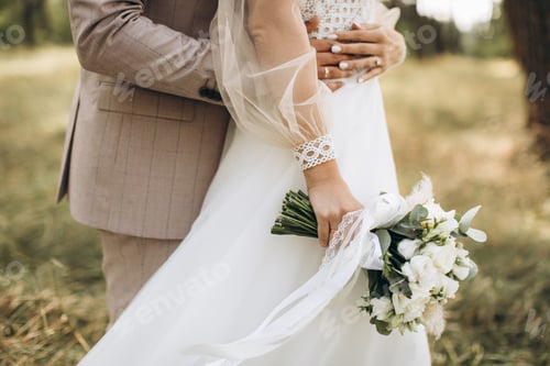 Preview: Close-up wedding couple bride and groom walk hand in hand through a pine forest