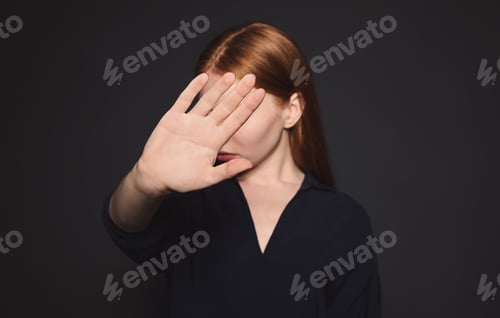Preview: Young woman making stop gesture against dark background, focus on hand