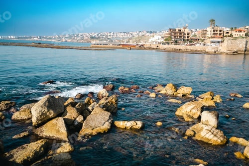 Preview: the ocean sits near many rocks on the shore of a city