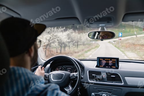 Preview: Man driving car while being on a day road trip.