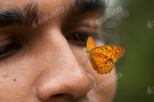 Preview: Butterfly sitting on a young man’s face, Symbiosis of man and nature.