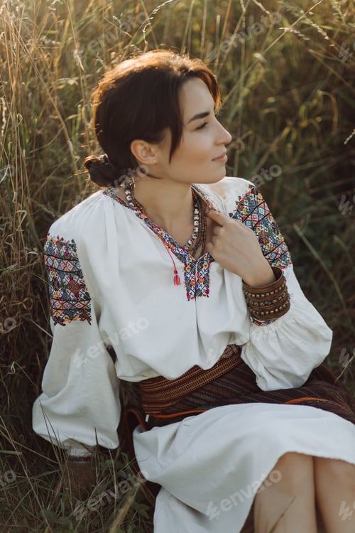 Preview: Young woman in traditional national embroidered shirt and skirt on nature at sunset.