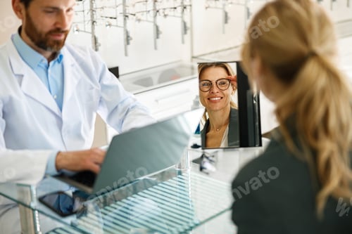 Preview: Woman looks in the mirror trying to choose glasses on the advice of an ophthalmologist
