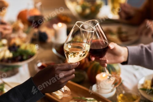 Preview: Close up of two people holding wine glasses at dinner table