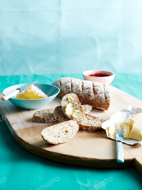 Preview: Sliced bread with butter and jam on a wooden board