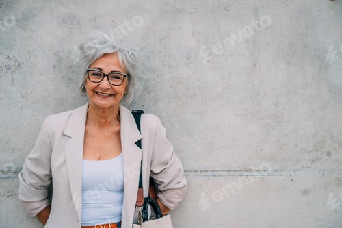 Preview: Smiling Senior Woman Leaning Against Concrete Wall
