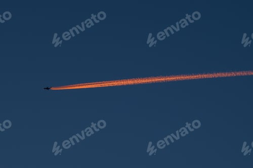 Preview: Beautiful night scene of a plane flying high in the sky and leaving a long orange trail behind it