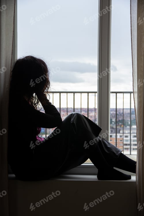 Preview: Woman in shadow sitting by the window with hand on head looking reflective, thinking, physiology
