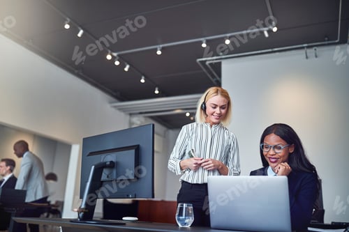 Preview: Two businesswomen smiling while looking at something on a laptop