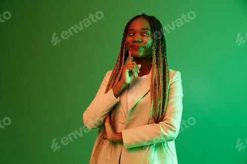 Preview: African american woman portrait business smile on green background in neon light, color mixed light