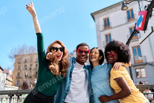 Preview: Excited multiethnic friends joking with heart shape sunglasses outdoors
