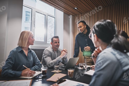 Preview: Smiling businesspeople discussing work together during a boardroom meeting