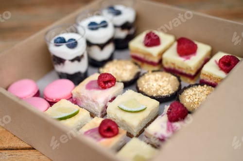 Preview: Selection of colorful and delicious cake desserts in box on table.