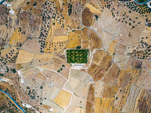Preview: Aerial view on a green football field during drought on sifnos island, Greece