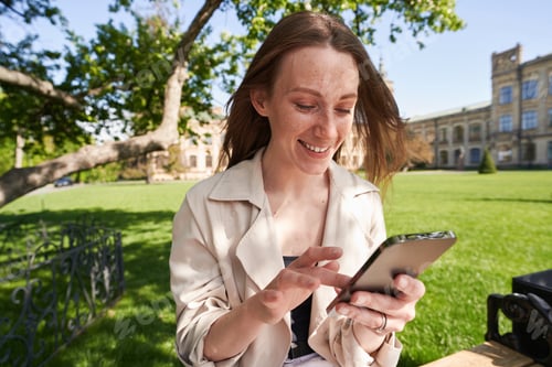 Preview: Smiling Woman Using Mobile Phone on University Grounds