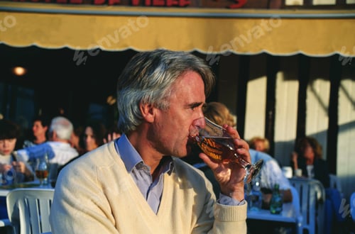 Preview: Man enjoying a beer in the early evening at a harbour side cafe in Honfleur, Normandy, France