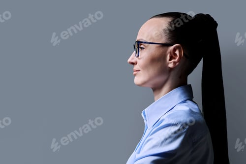 Preview: Profile view of 30s serious woman, gray background, copy space