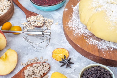 Preview: Front view of raw pastry flour on round wooden board grater hazelnuts fresh fruits chocolates on