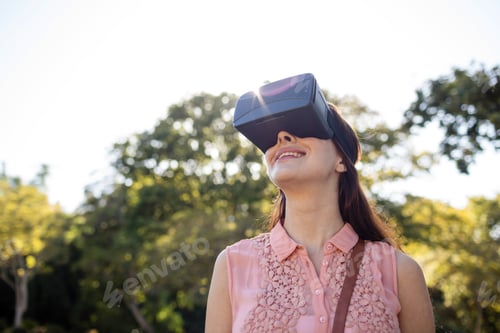 Preview: Smiling woman using a VR headset in the park