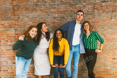 Preview: Young multicultural team posing cheerfully against brick wall