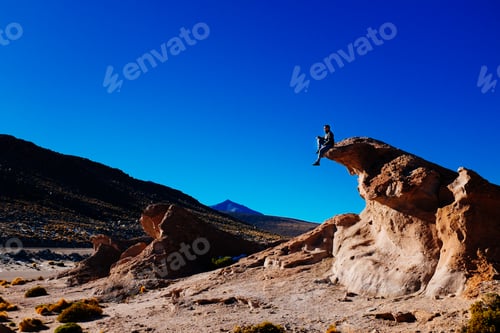 Preview: Man sitting high on a rock in the middle of Uyuni salt flat
