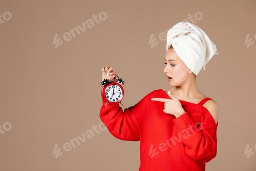 Preview: front view young female holding clocks with towel on her head on pink background woman hair shower