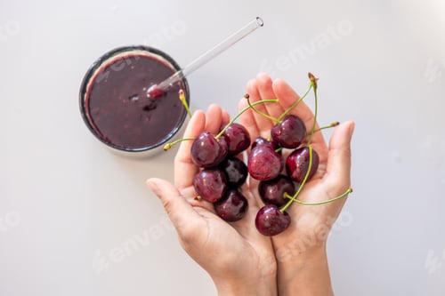 Preview: Smoothies and ripe cherries in female hands.
