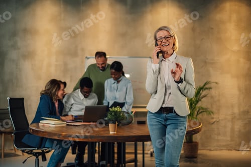 Preview: Portrait of a senior businesswoman in a modern workplace talking on a phone