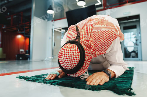 Preview: Young arab muslim man praying in office on carpet