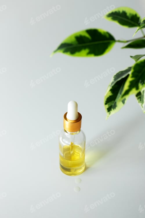 Preview: Serum essence in glass bottle and leaves on white background