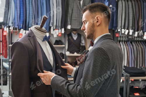 Preview: Man choosing clothing on mannequin in boutique