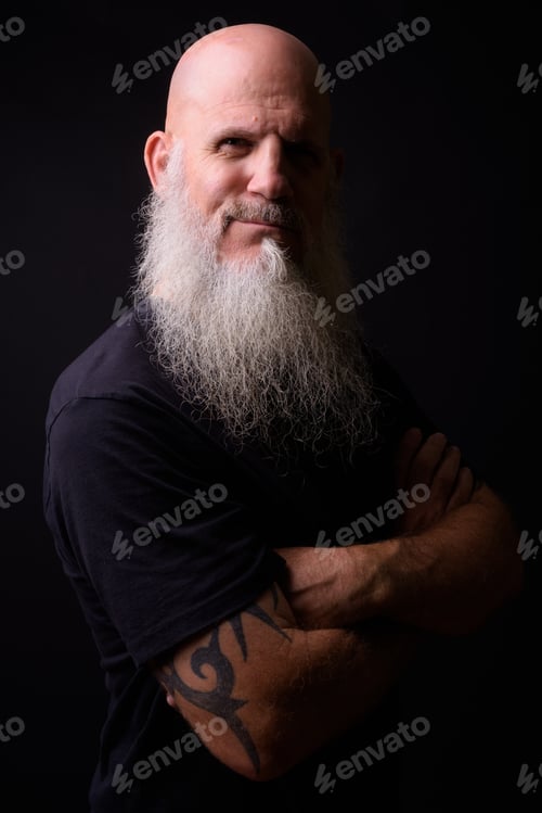 Preview: Mature bald bearded man against black background