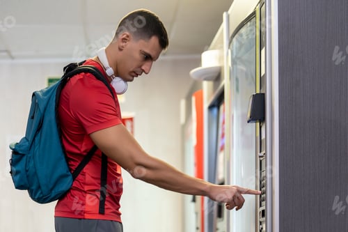 Preview: Athlete in gym consuming drink from food vending machine