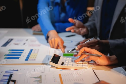 Preview: Business team working late and analyzing financial statistics using calculator and documents