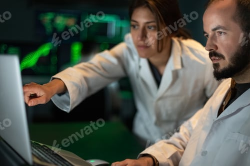 Preview: Female scientist shows doctor colleague experiment results in the laptop. Working in laboratory.