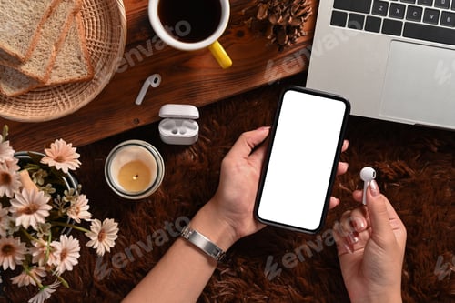 Preview: Close up view woman holding smart phone and wireless earphone.