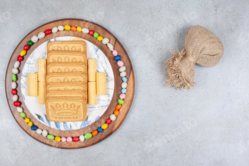Preview: A sack next to a platter of biscuits encircled by candy on a wooden board, on marble background