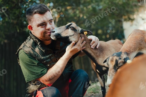 Preview: Caretaker with down syndrome taking care of animals in zoo, stroking goat. Concept of integration