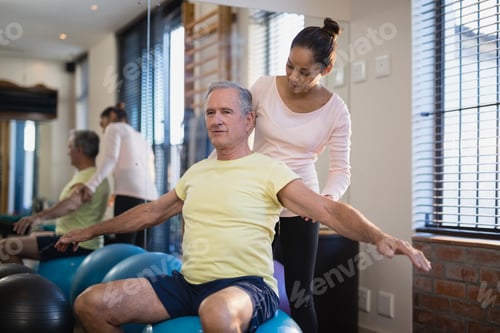 Preview: Female therapist looking at male patient exercising with arms outstretched