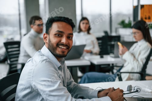 Preview: Man is sitting in front of his colleagues. Four people are working in the office together